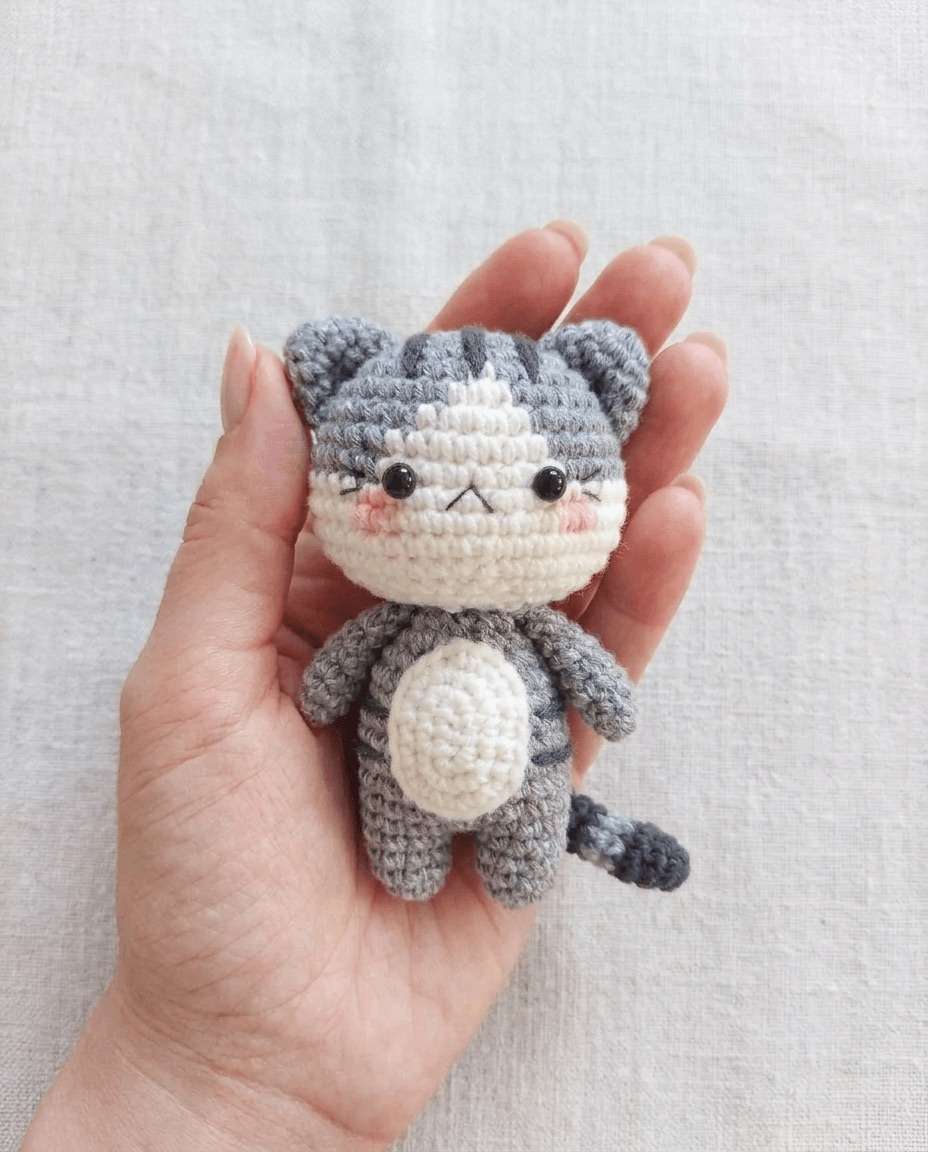Crochet amigurumi cat with tan and cream stripes, a soft cream belly patch, and embroidered whiskers