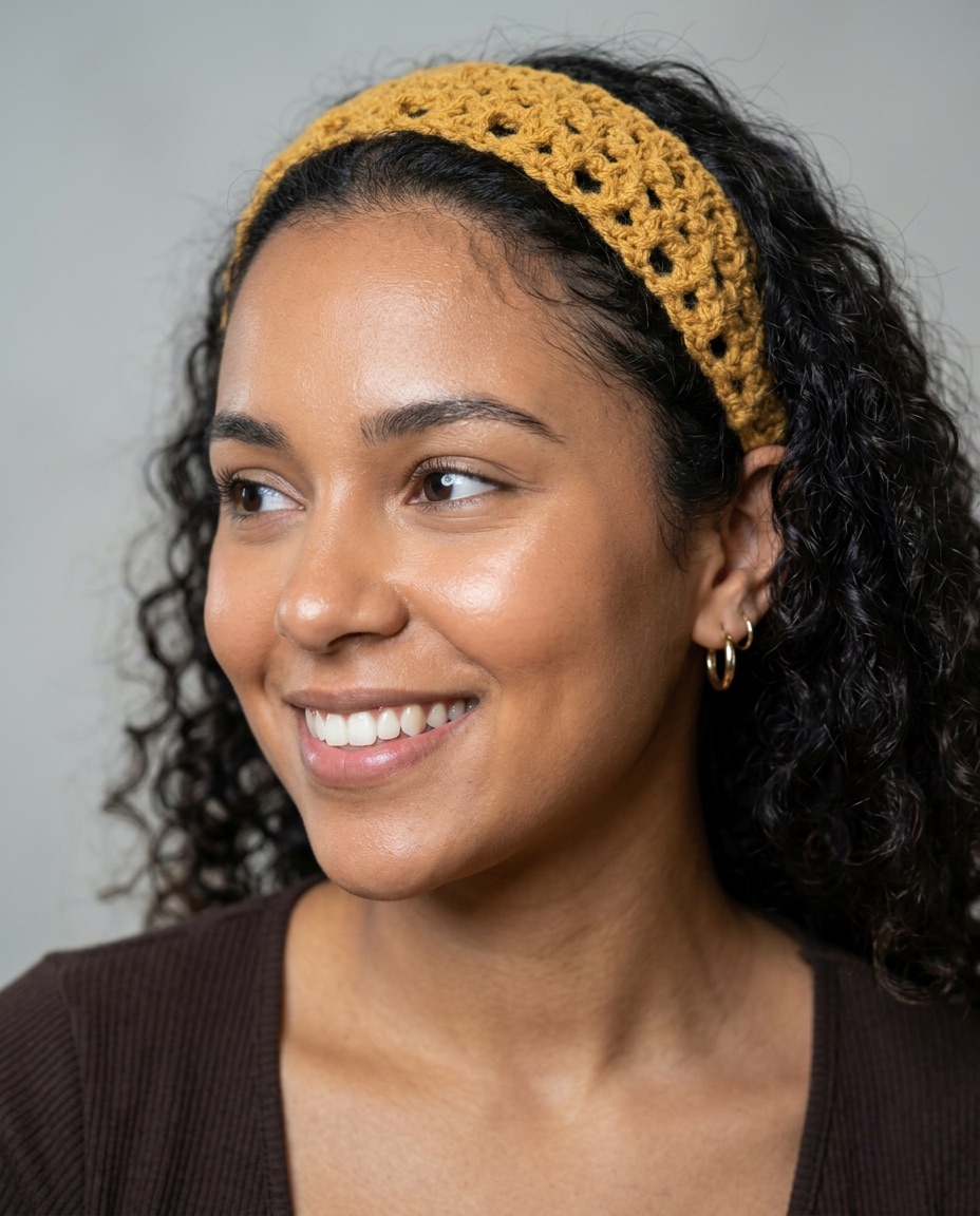 Mustard yellow openwork mesh crochet hairband worn over curly hair