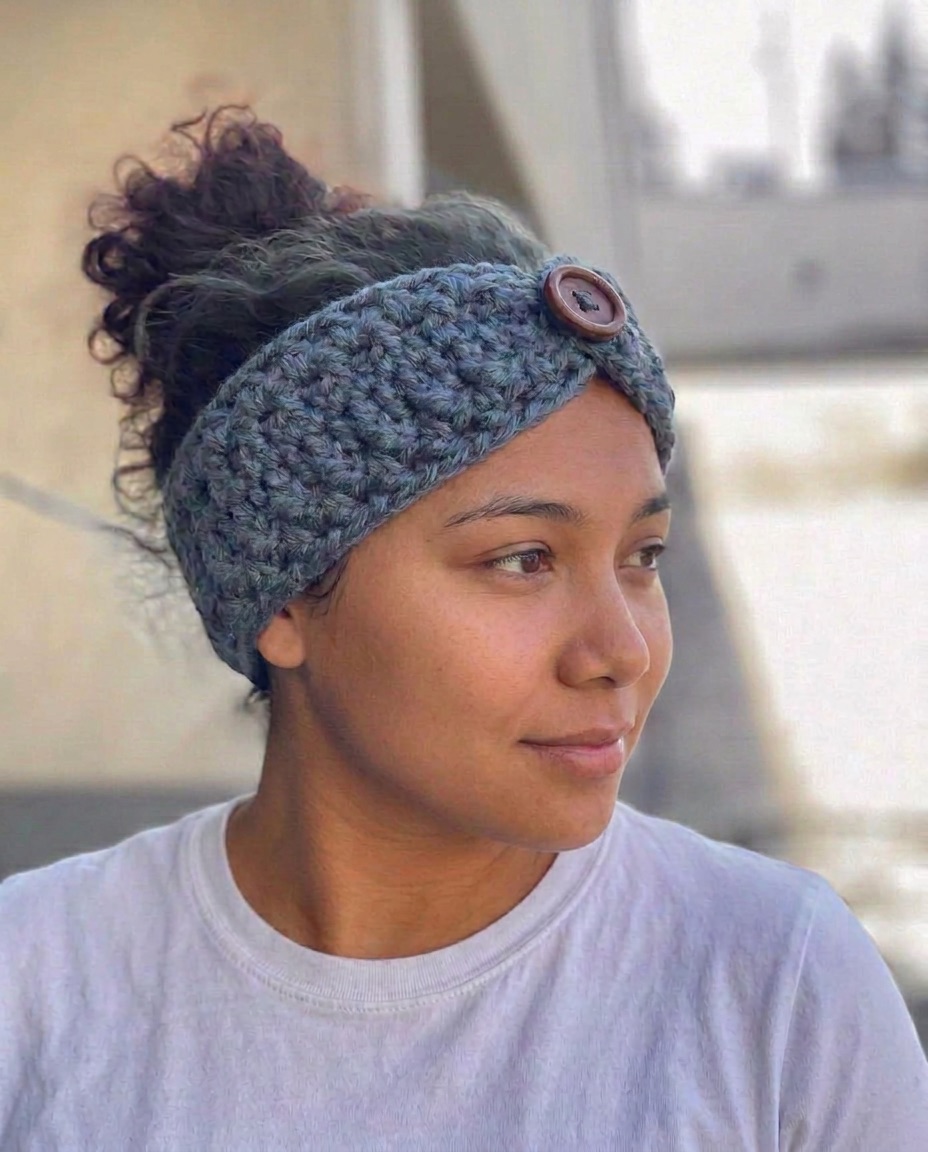 Grey blue chunky crochet ear warmer with a wooden button, worn with a high bun