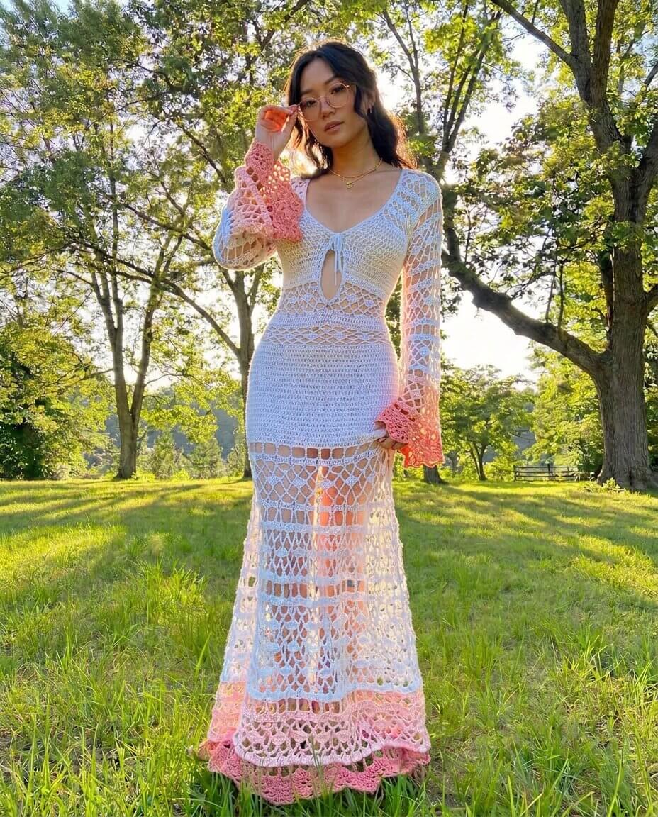 White and pale pink ombre crochet lace maxi dress with long flared sleeves a corseted lace up front bodice and a shell stitch skirt with a picot edge