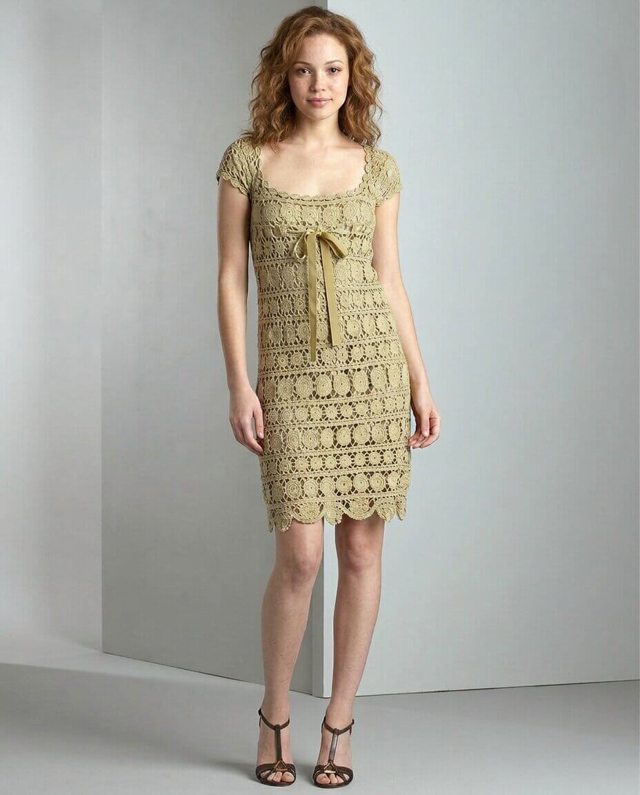 Sage green crochet dress with cap sleeves an allover floral medallion stitch pattern a scalloped hem and a satin ribbon bow tied at the bust