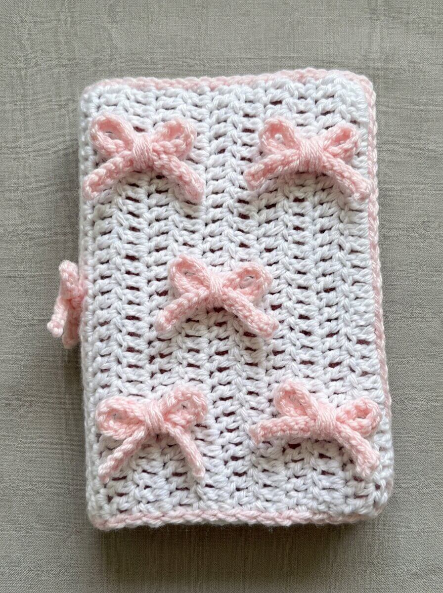 White crochet Bible cover scattered with small pink crocheted bows