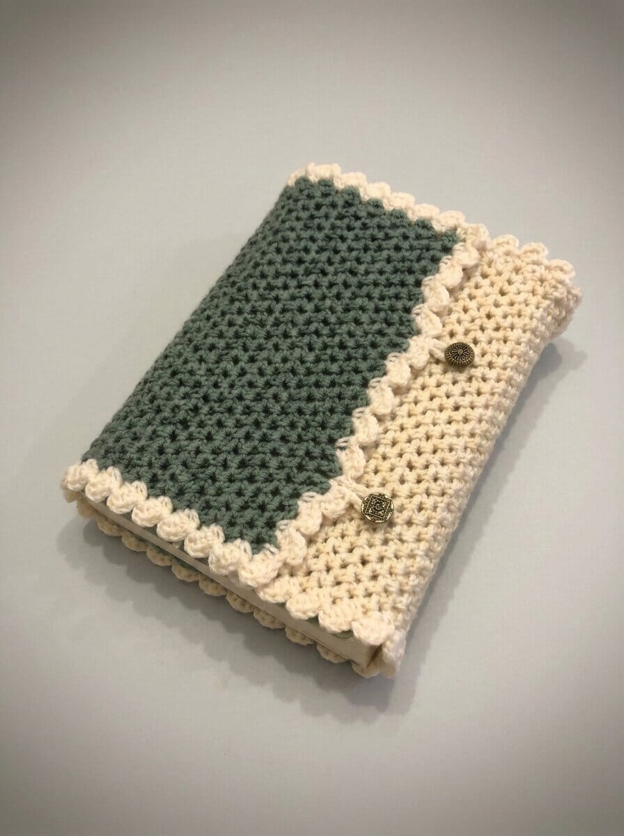 Two tone crochet Bible cover in sage green with a scalloped cream border and two decorative buttons