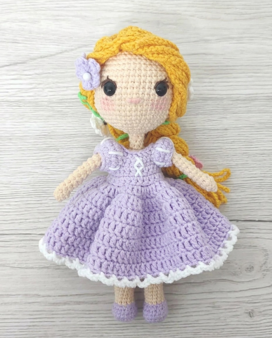 Crochet Rapunzel amigurumi doll with long golden braided hair woven with flowers, wearing a lilac puff sleeve dress with a white picot hem