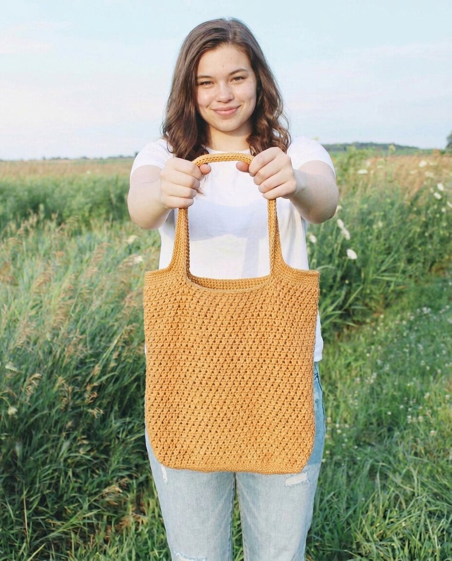 Golden yellow crochet market tote with an openwork cross double crochet stitch and long flat shoulder straps